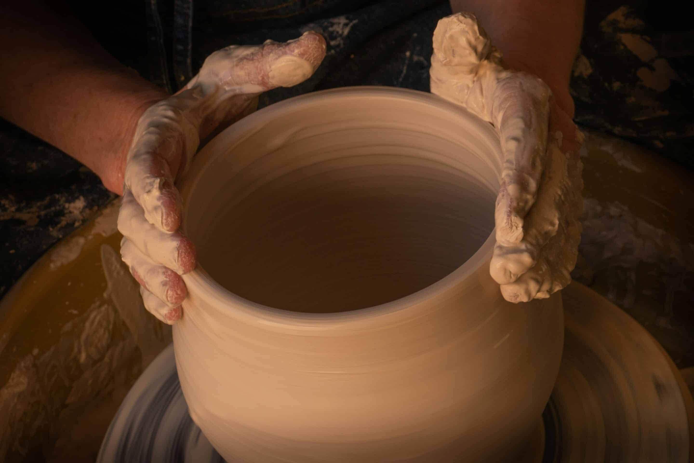 Clay in the potters hand A clay pot on a potters wheel supported and formed by two hands