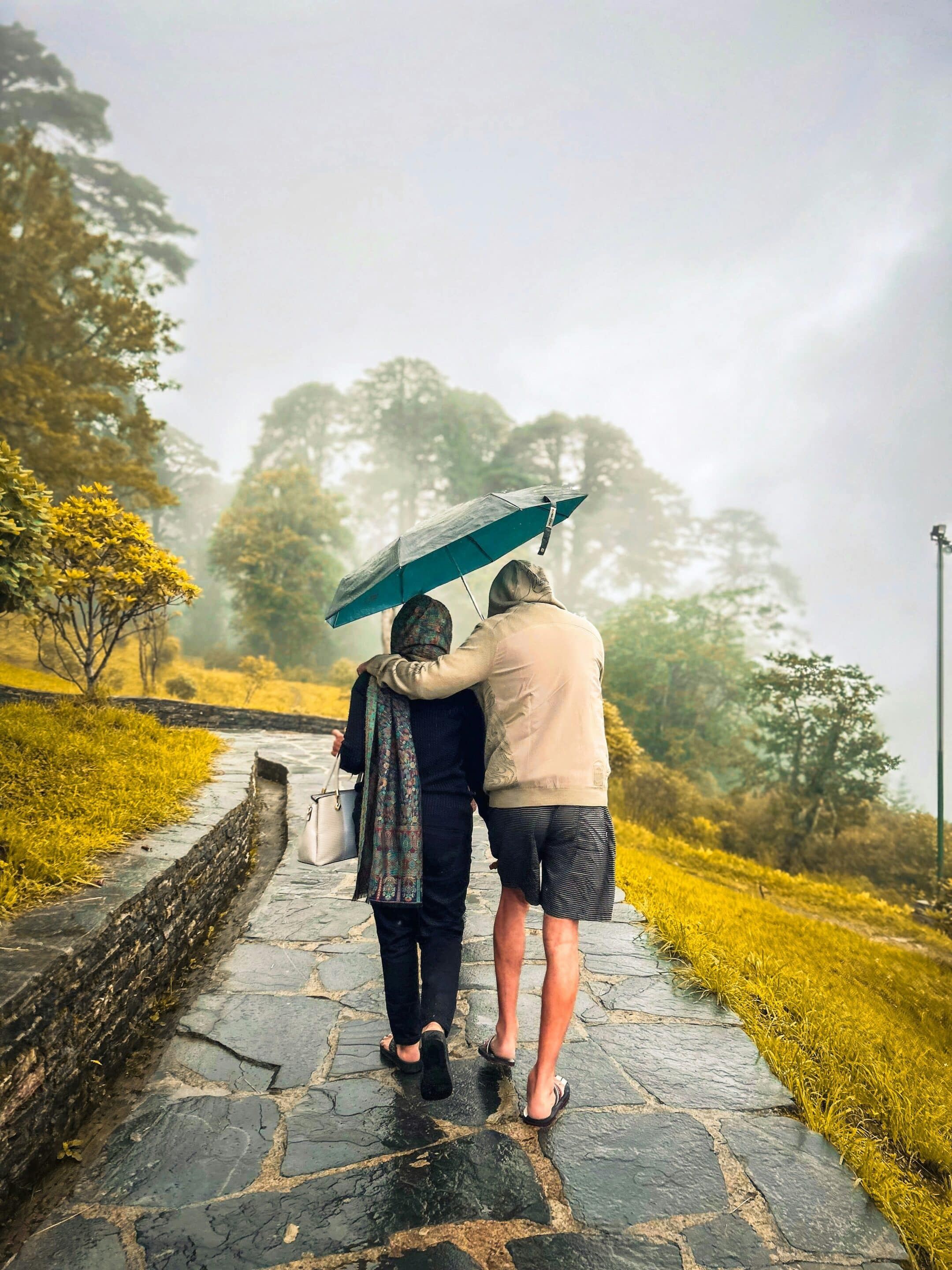 Two people sharing an umbrella walking down a path