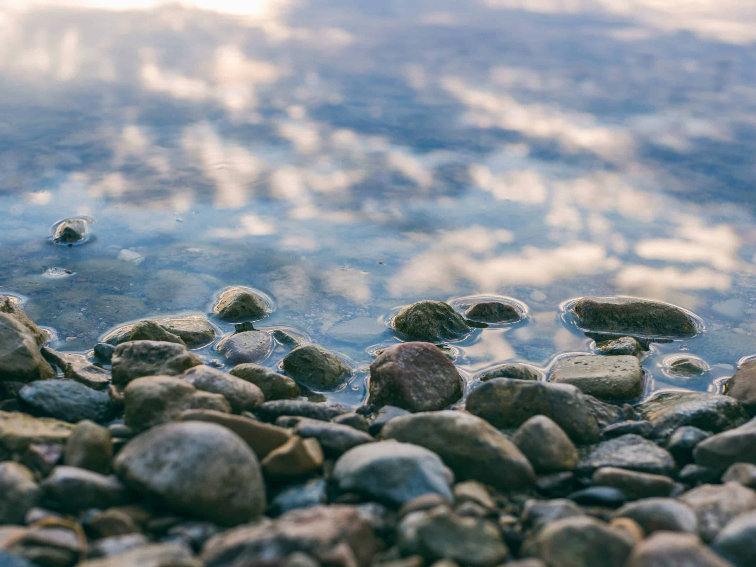 Small stones lead the eye to the still water of a riverbed.
